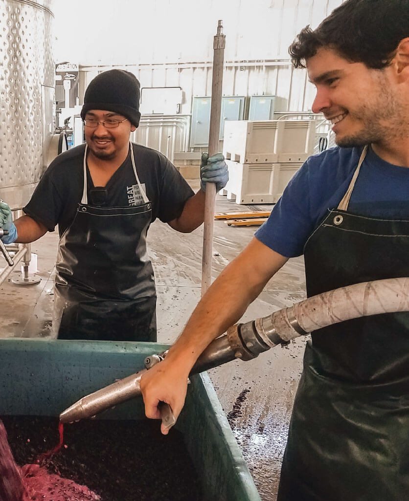 Two people putting a red liquid inside a container