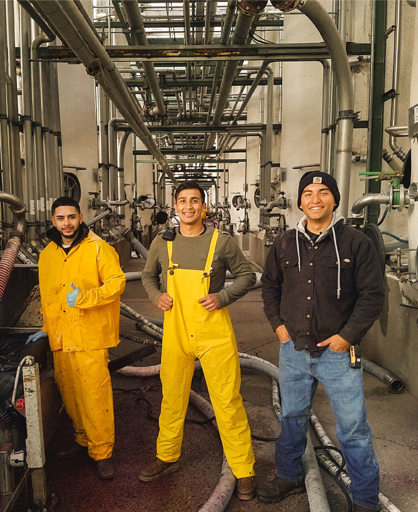 Three people standing inside a factory setting